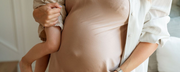 Close-up of a pregnant woman holding a child, symbolizing the journey of motherhood and the importance of nutrition at every stage of pregnancy. - WeNatal